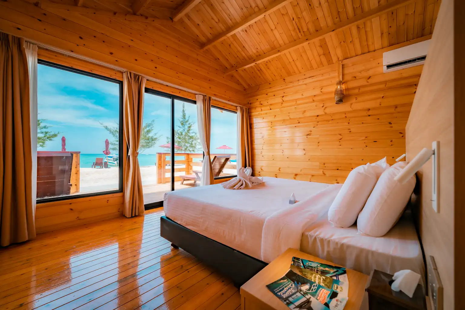 Beachfront premium villa interior with a large bed facing the ocean through floor-to-ceiling windows.